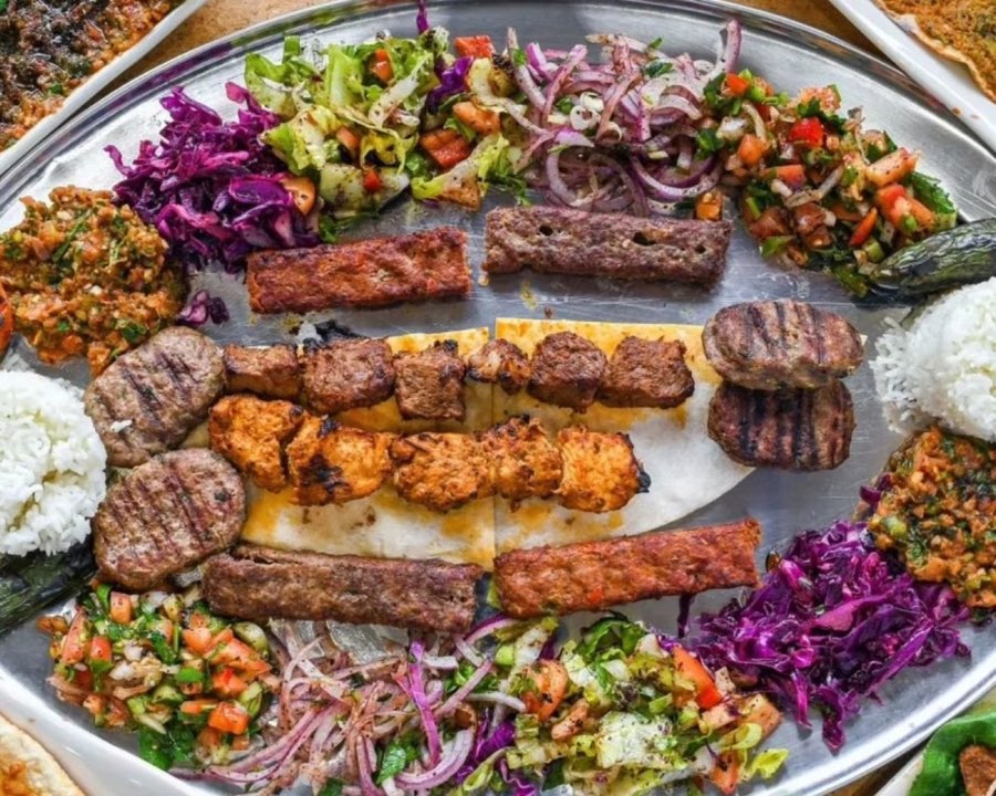 Mixed grilled meats with rice, chopped salads and flatbread on a large platter