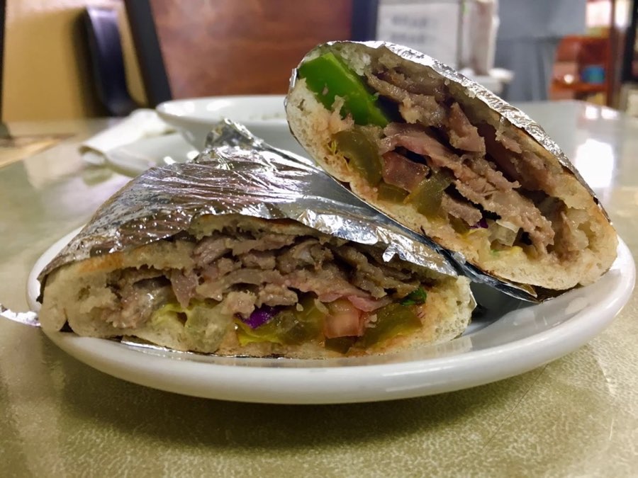 Bilad beef shawarma sandwich in Iraqi bread, cut in half with peppers and vegetables.