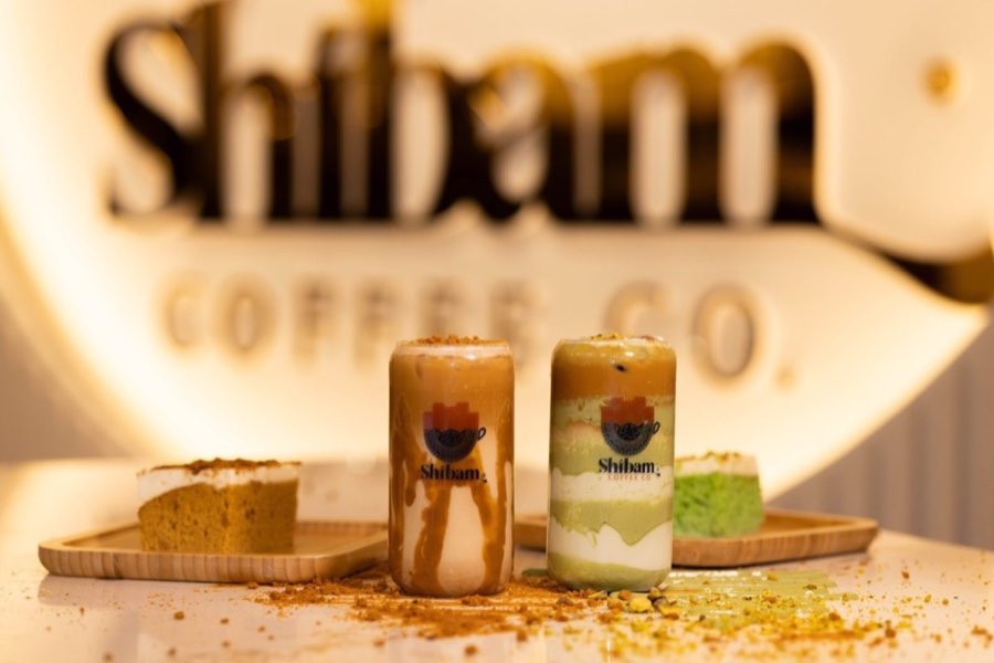 Lotus and pistachio iced lattes with matching cake slices at Shibam Coffee Co.