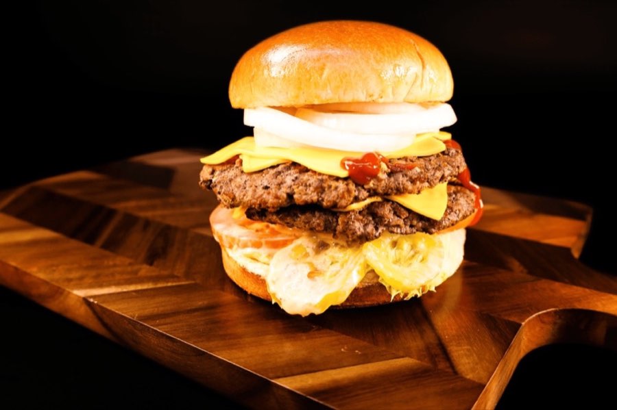 Yummy Burgers beef burger with cheese and lettuce on a wooden board.