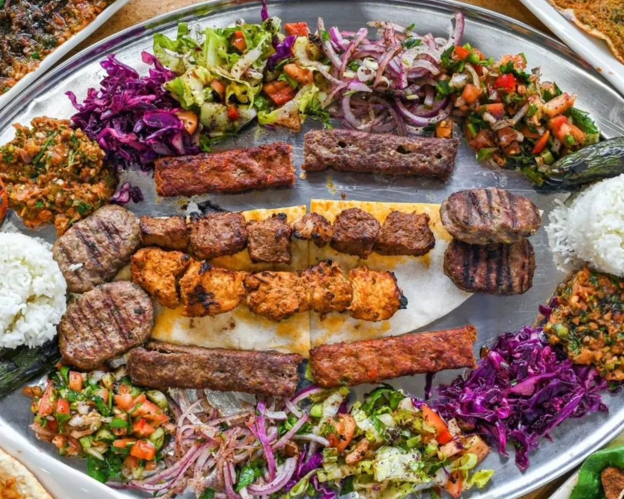 Mixed grilled meats with rice, chopped salads and flatbread on a large platter