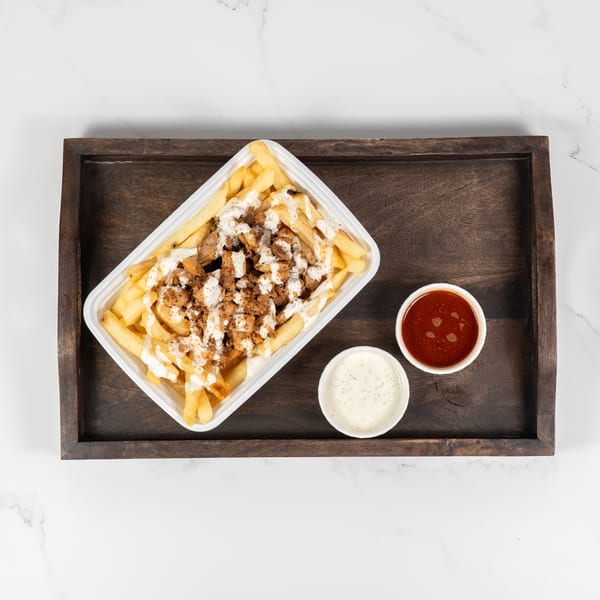 Chicken-topped fries with white sauce and two dipping sauces