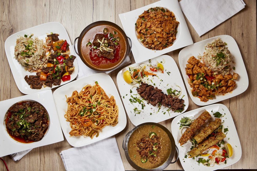 Overhead spread of rice plates, noodles, curries and grilled kebabs