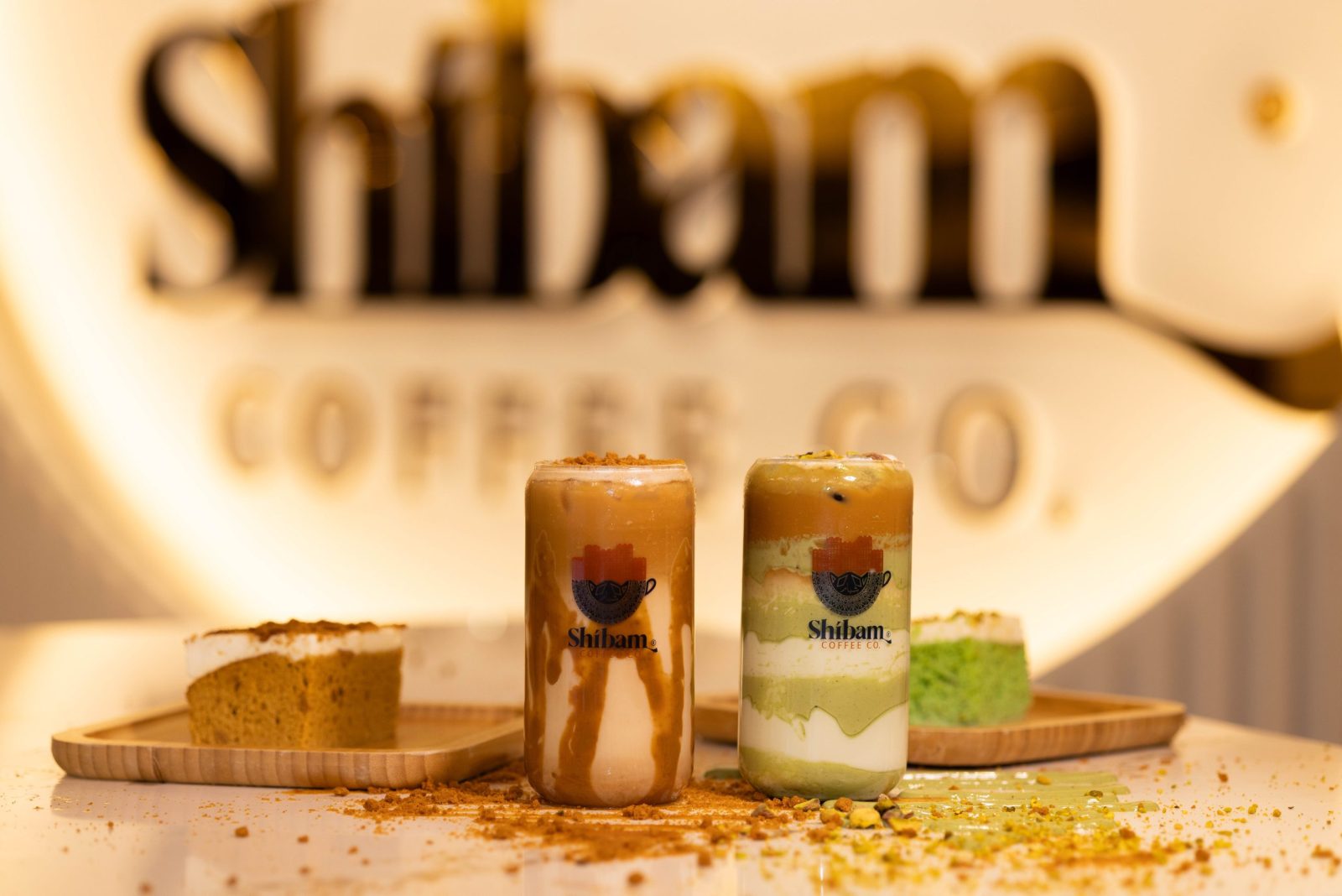 Lotus and pistachio iced lattes with matching cake slices at Shibam Coffee Co.